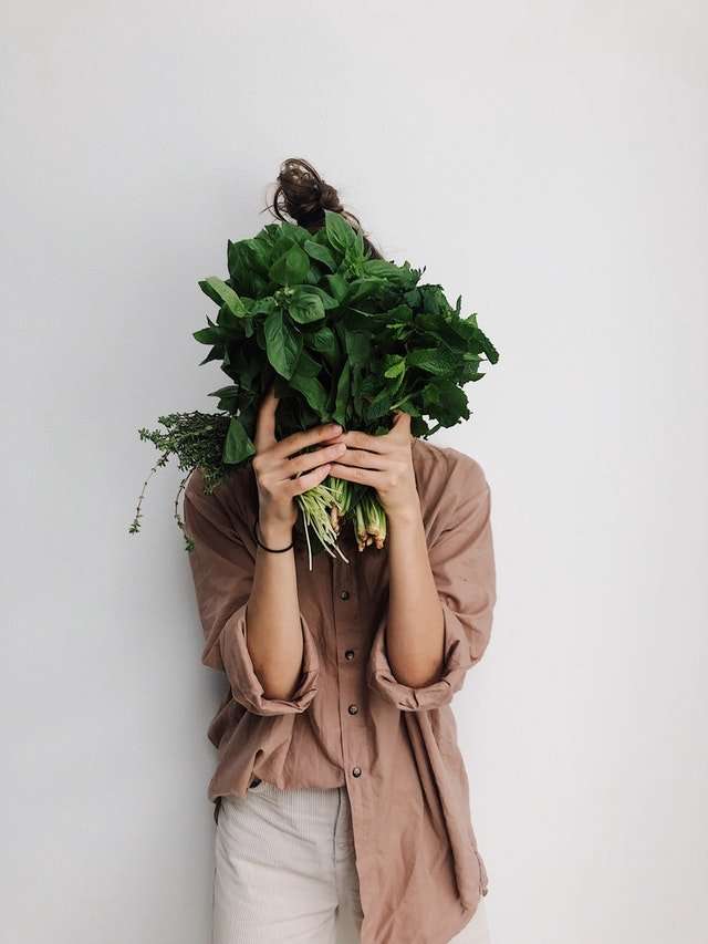 vegetarian lady hiding behind vegetables