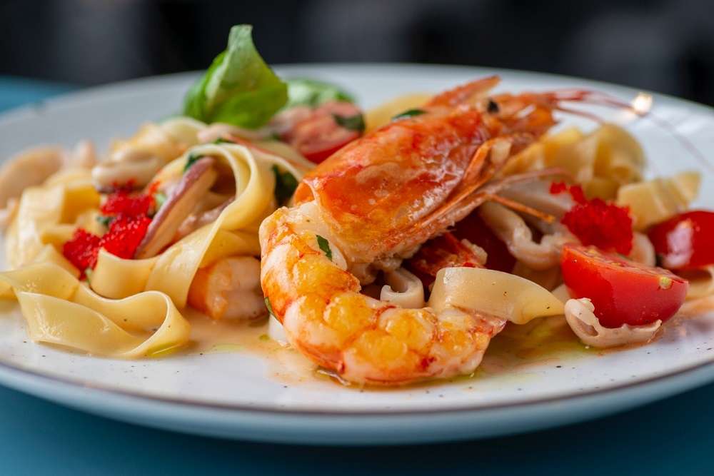 shrimp on a plate with pasta and vegetables
