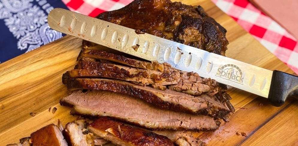 large cut of meat wit a carving knife on a cutting board.